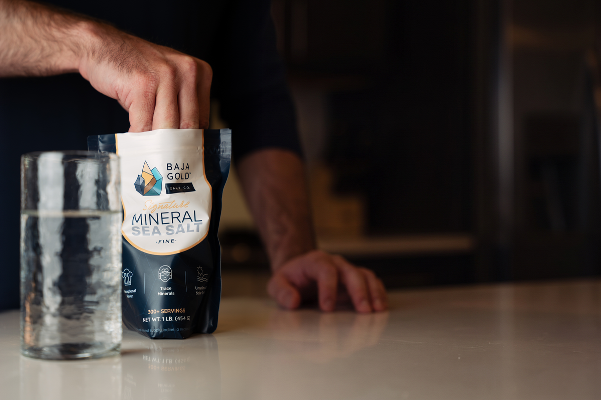 Adding a pinch of Baja Gold Natural Grain sea salt to a glass of water
